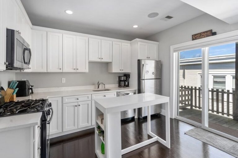 Classic white Shaker cabinet kitchen with Caesarstone countertops, custom kitchen island with slate counter and stainless steel appliances and a master bedroom with bay windows and custom closet. #ashmontstreet #Dorchester #N6 #N6Properties #RealEstate #Development #Boston #ApartmentforRent #Construction #DiarmaidMcGregor #BostonHomes #PropertyManagement #pennywhitetiles